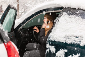 Woman calling for assistance from her car after an accident in the snow